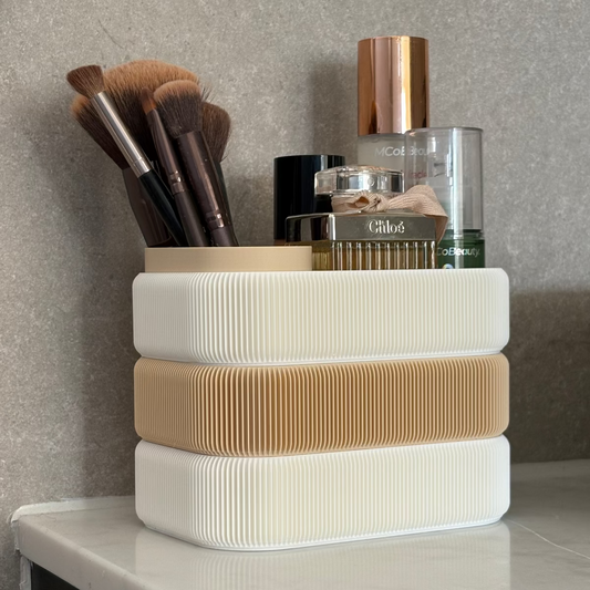 Stack of white and beige containers with makeup brushes and products on a vanity