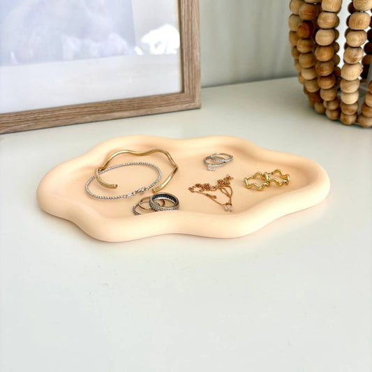 Coud tray 3d printed styled with bracelets, rings, necklaces on a white table with a lamp base and photo frame