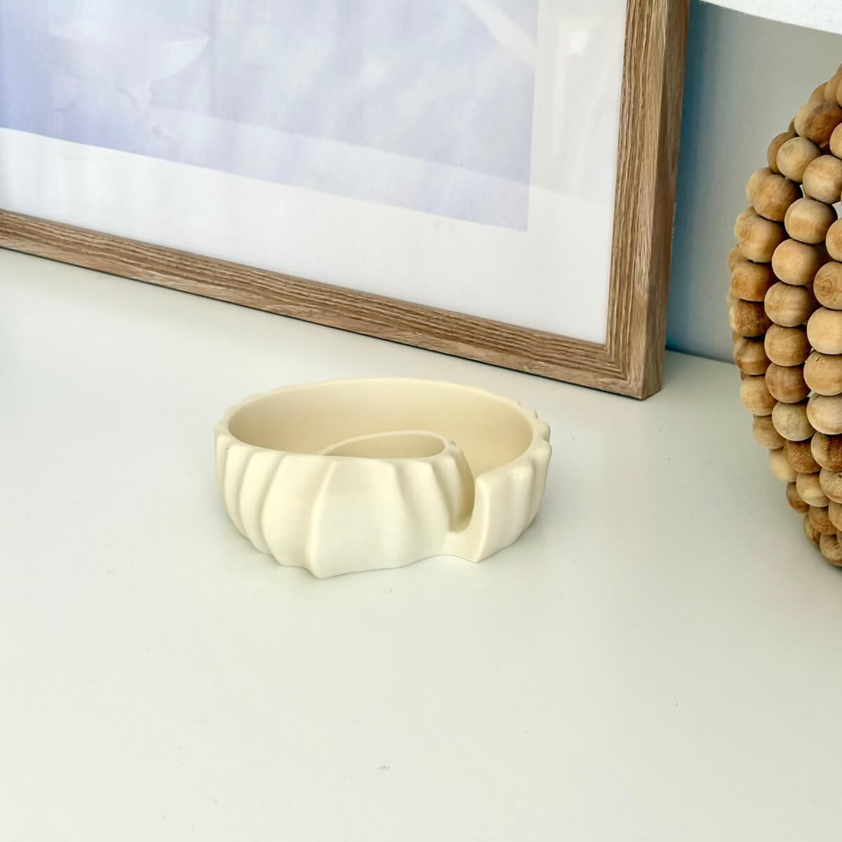 Ammonite Tray 3D printed styled on a white surface with a picture and lamp
